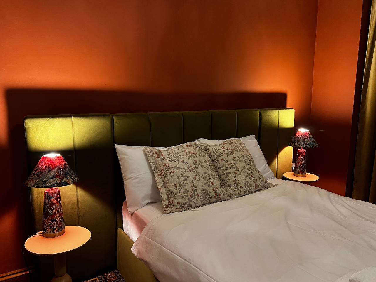 Bedroom with olive velvet headboard and warm lamp light